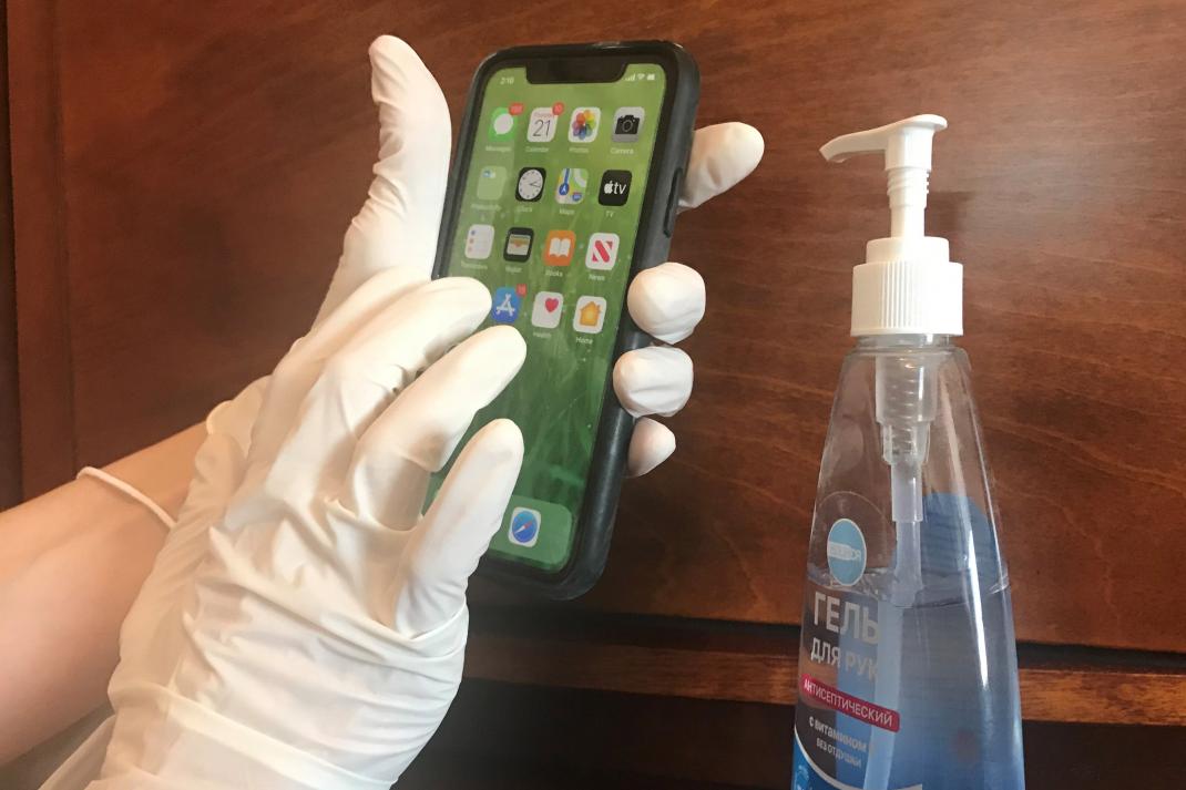 Женщина в медицинских перчатках держит в руках iPhone.