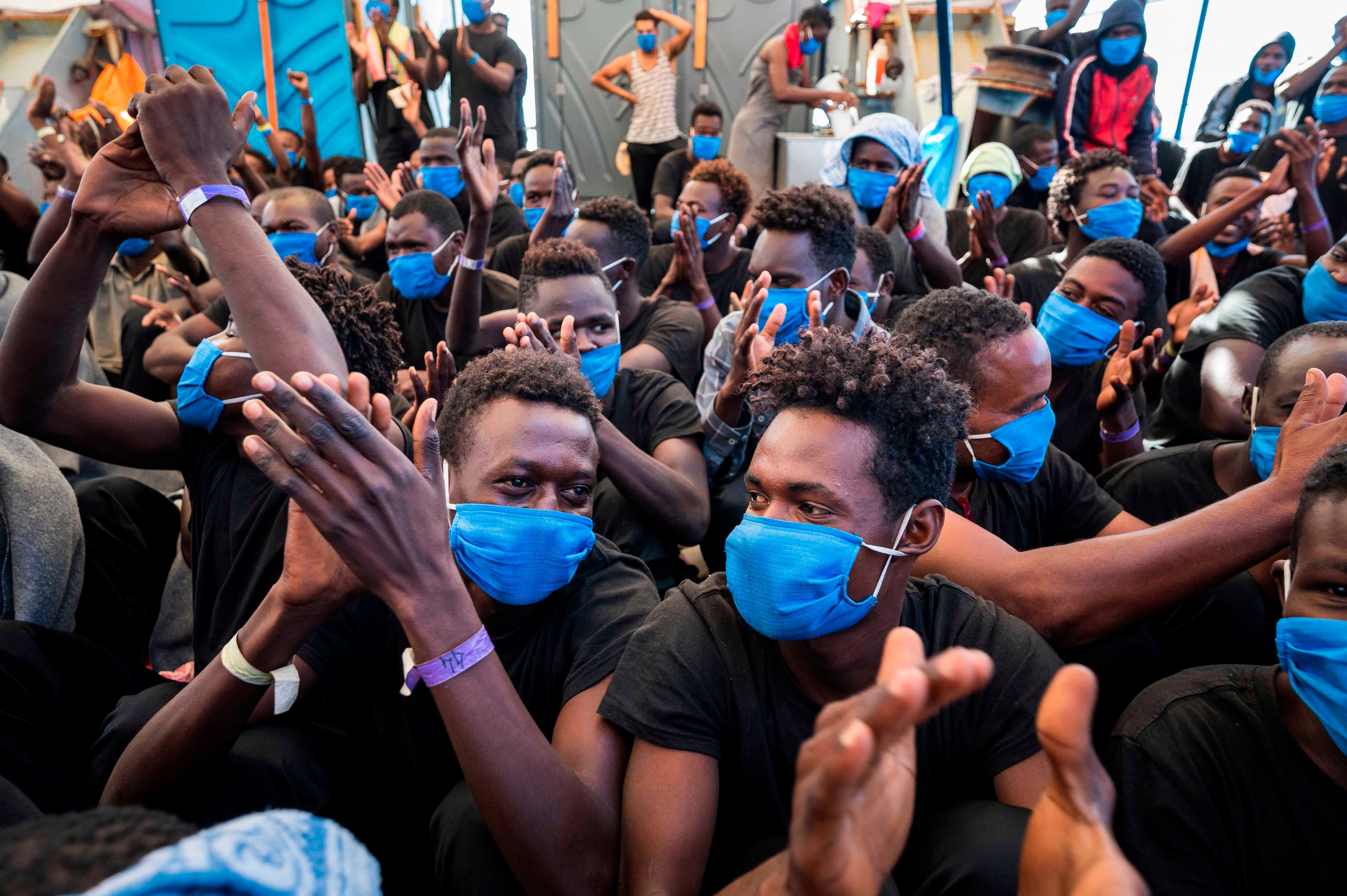Uomini a bordo della Sea-Watch 4, una nave di soccorso non governativa, gioiscono il 1° settembre 2020, quando apprendono di avere il permesso di sbarcare a Palermo, in Sicilia, il giorno dopo. 