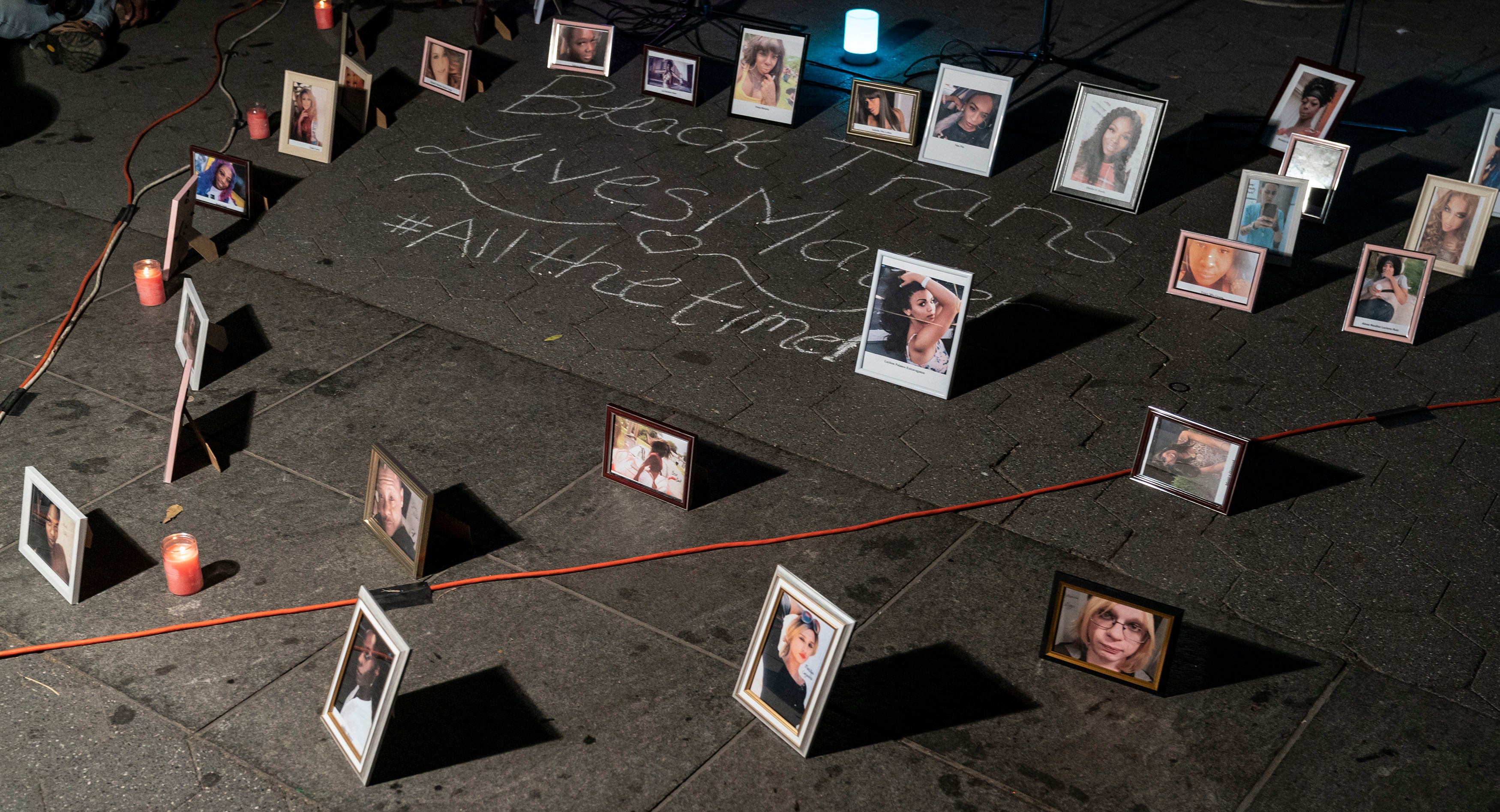 Framed photos placed on the ground around chalk writing that says "Black trans lives matter #allthetime"