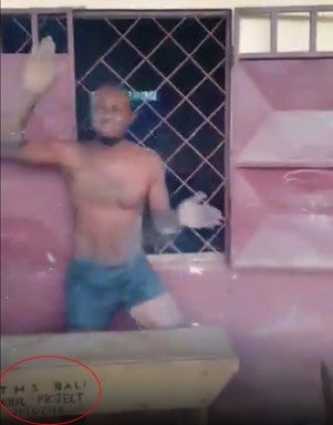 A shirtless man gesturing