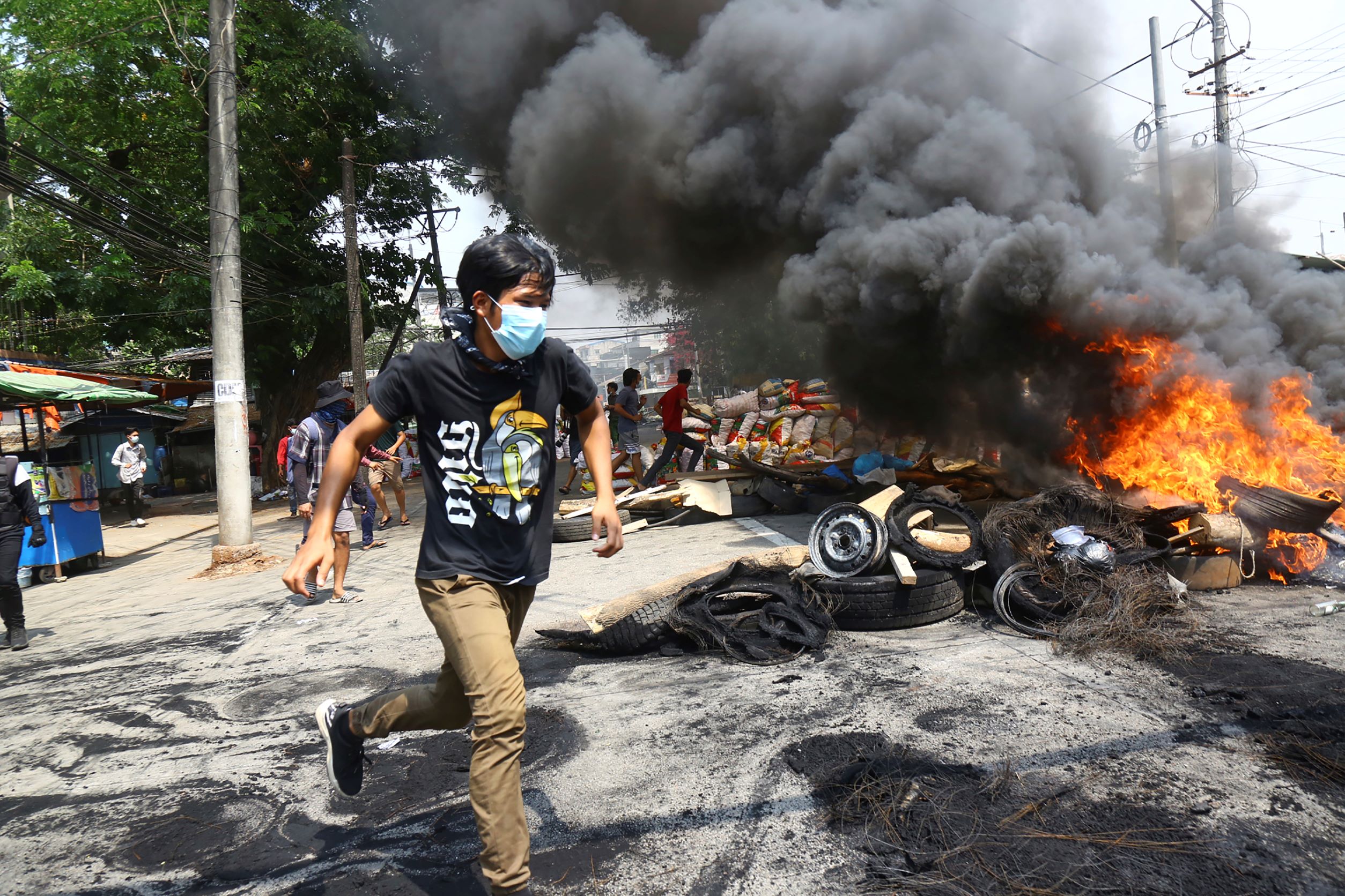 Un homme courait devant des pneus brûlés, lors d’une manifestation anti-coup d'État tenue à Yangon (Rangoun) au Myanmar, le 28 mars 2021, pour protester contre le coup d’État militaire du 1er février 2021.