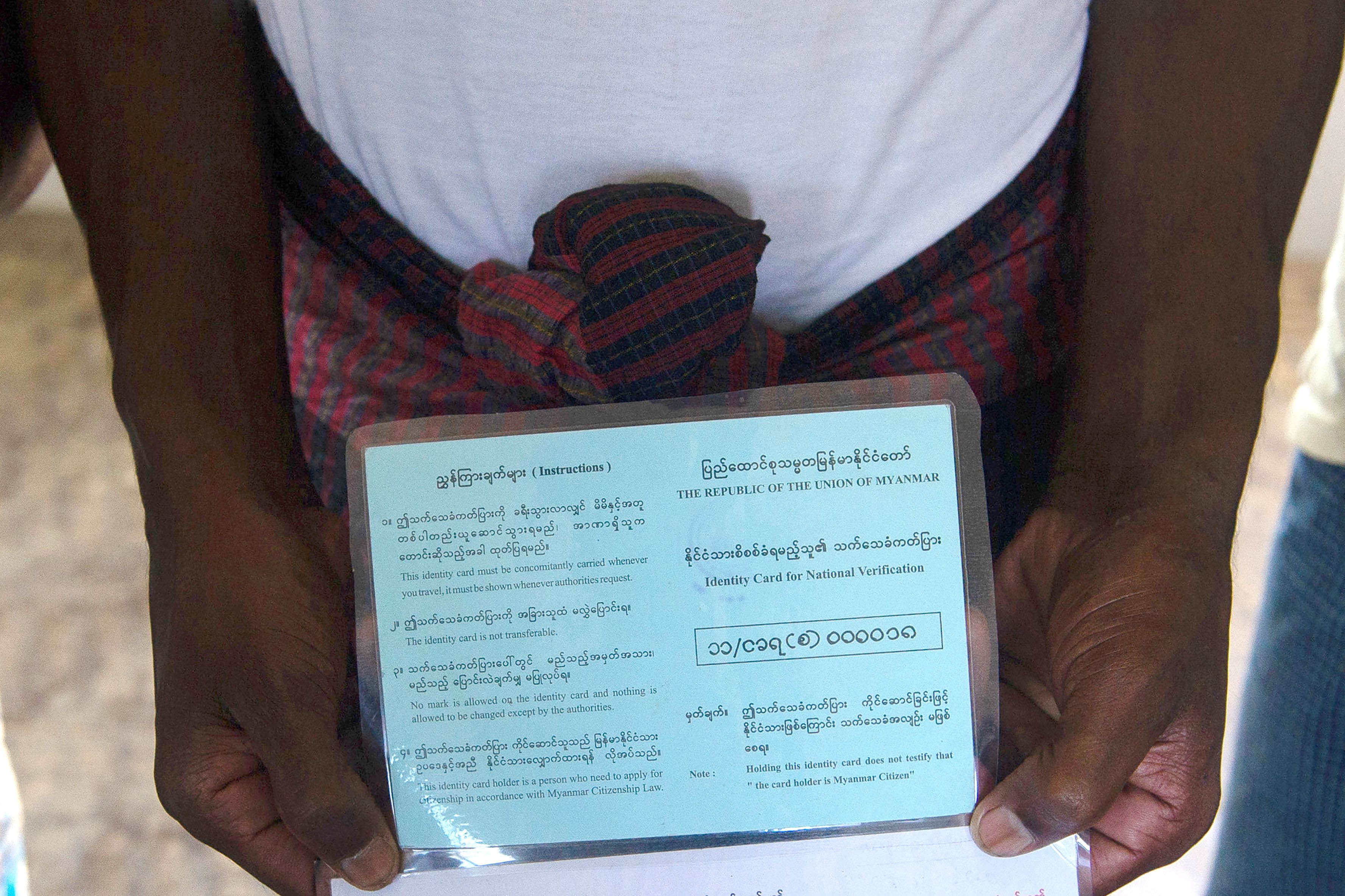 A man holds a blue identity card