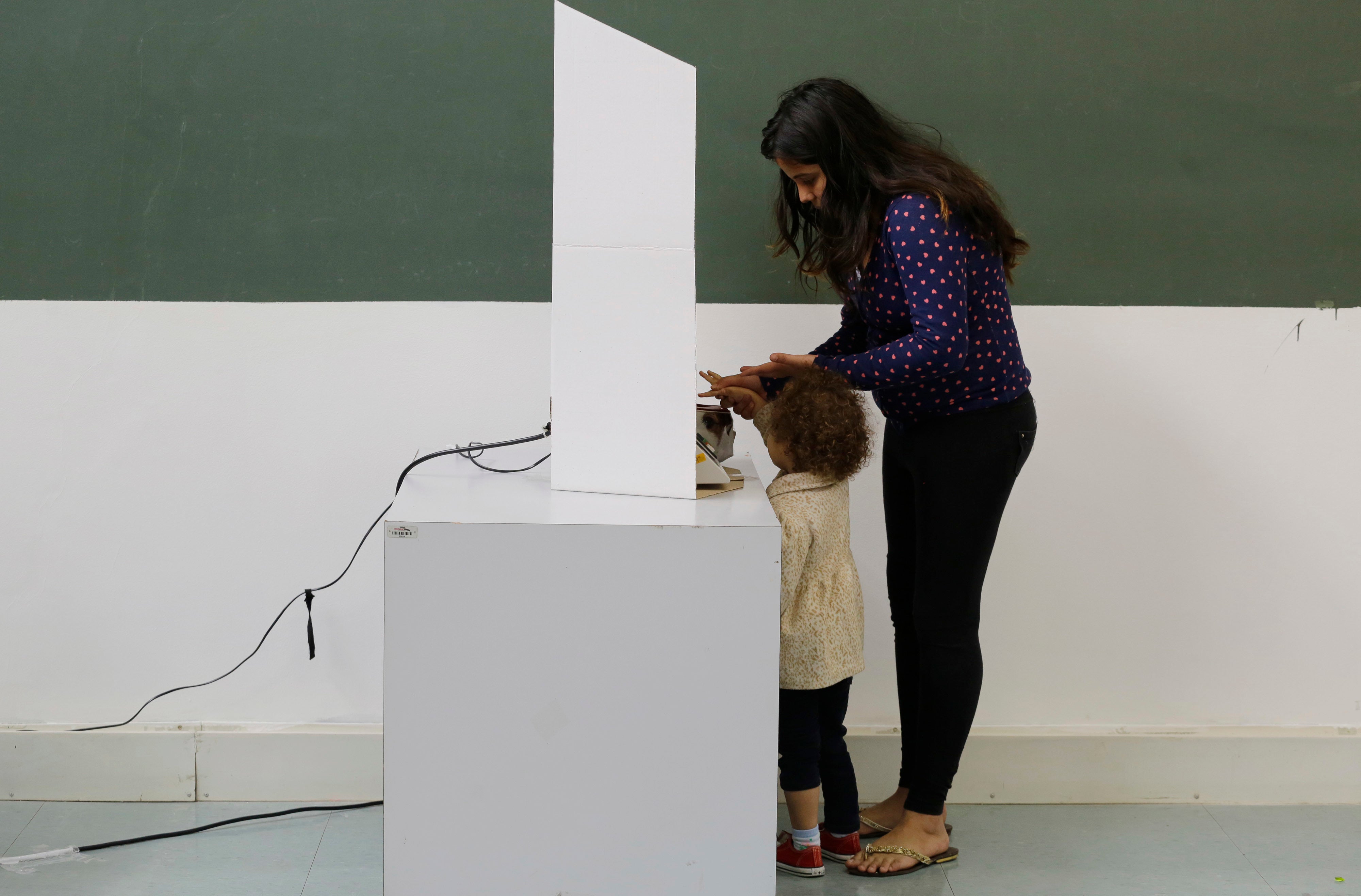 Uma mulher, acompanhada por uma criança, votando nas eleições municipais em São Paulo, Brasil, 2 de outubro de 2016.