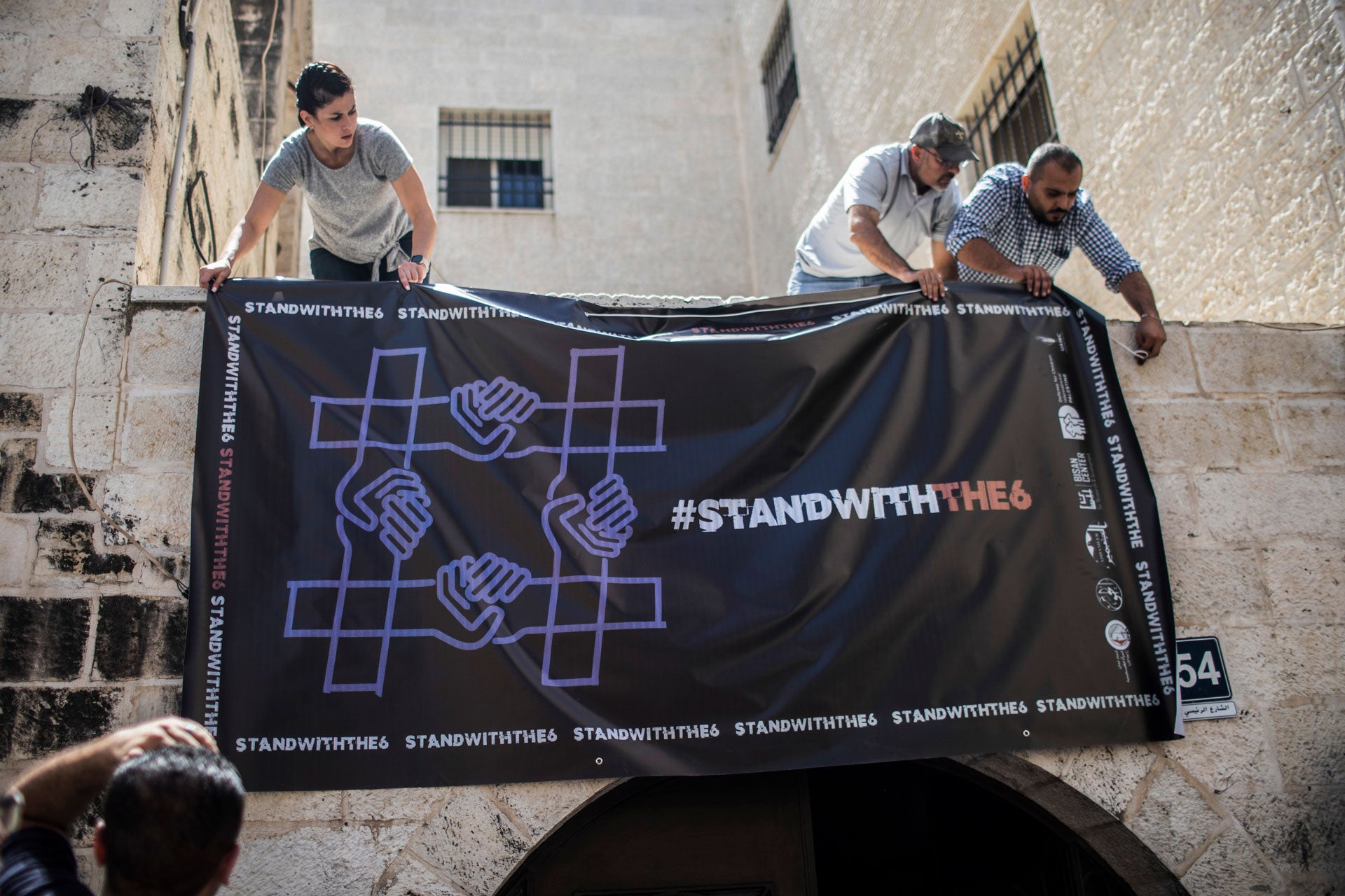 Activists hang a poster outside a Palestinian civil society organization