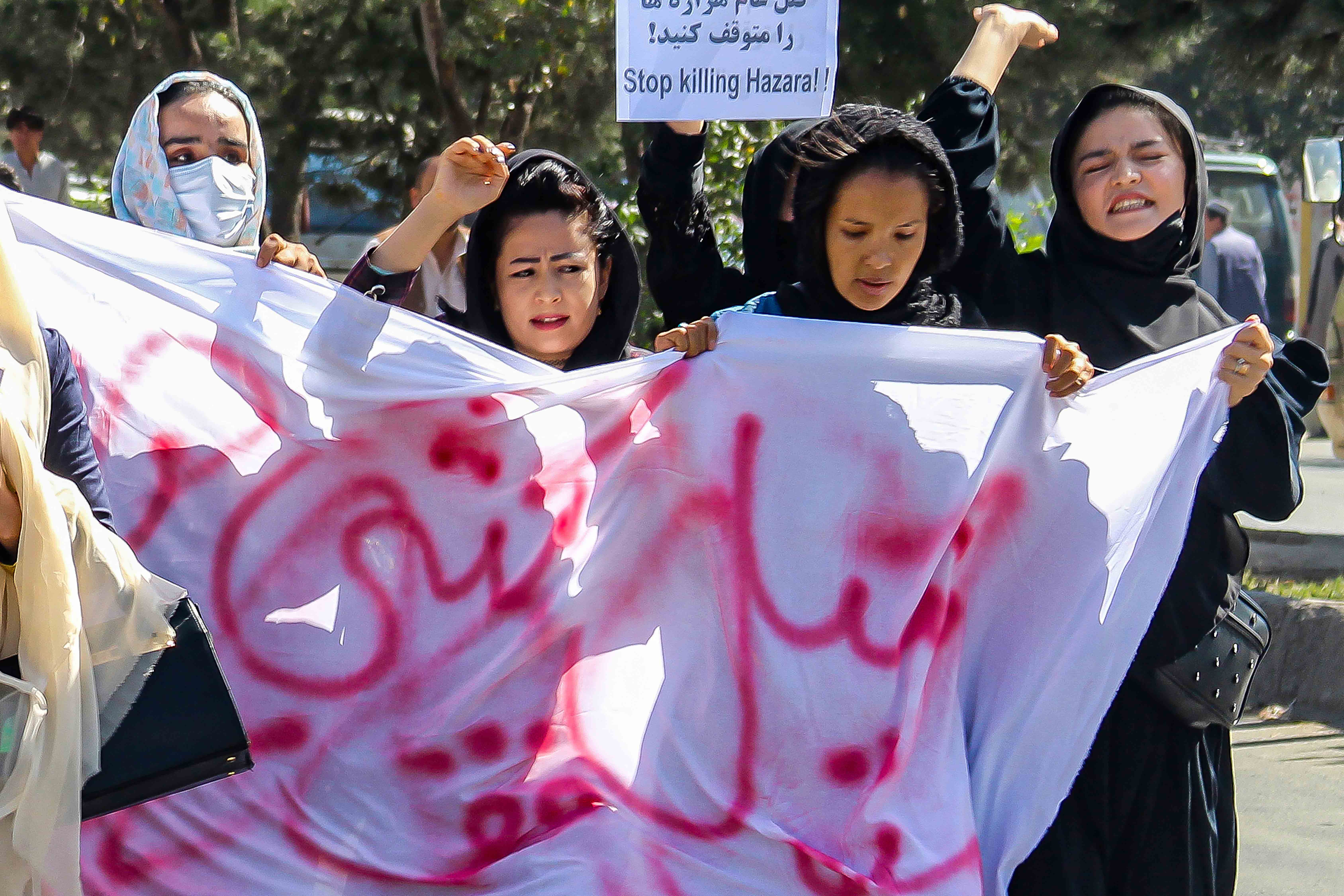 Women in hijabs march with protest signs