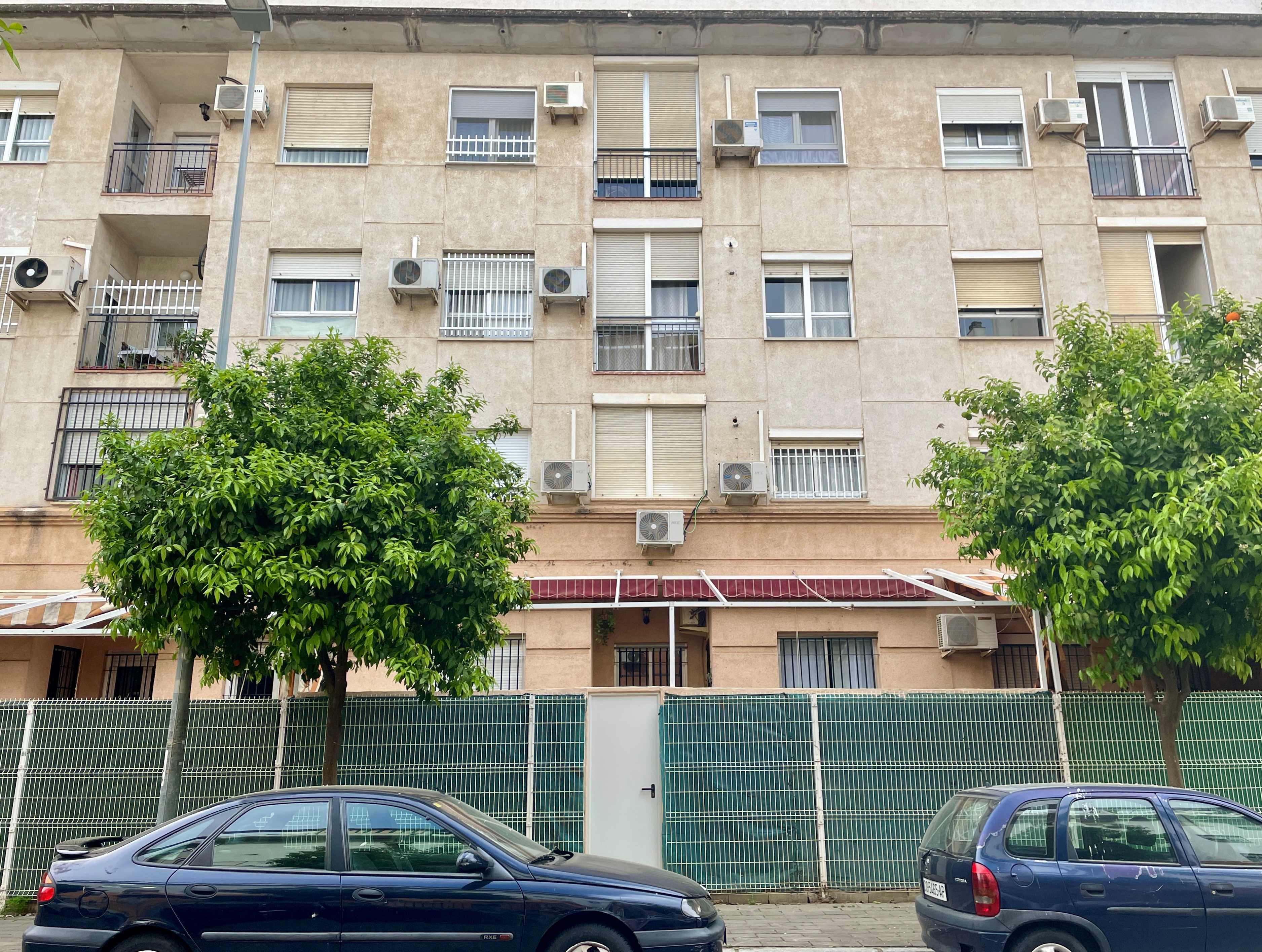 Un immeuble résidentiel à Séville (Andalousie, Espagne), avec de nombreuses unités de climatisation extérieures et deux arbres verts.