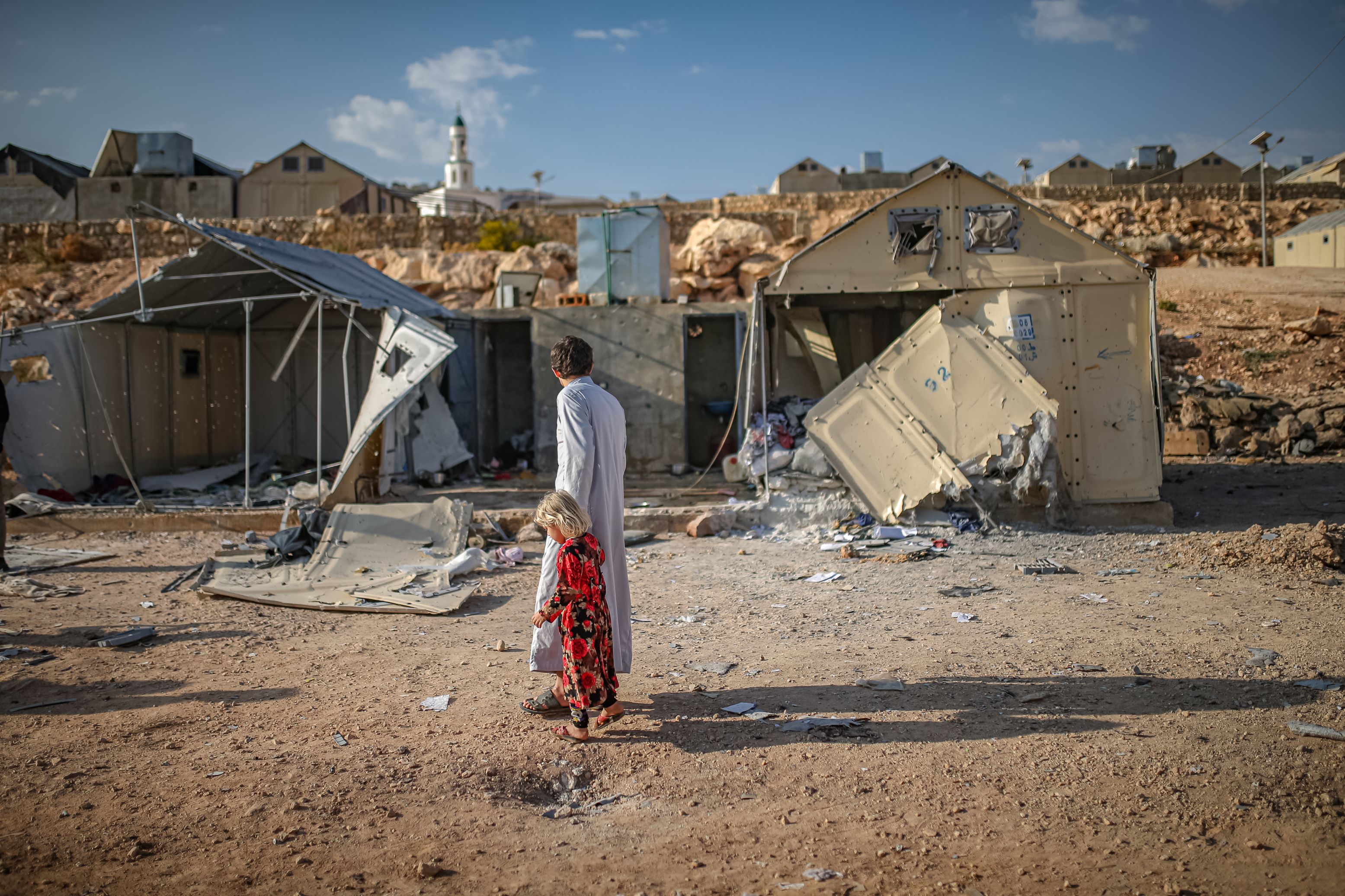 أشخاص يقيمون الأضرار الناجمة عن الهجوم بالذخائر العنقودية الذي شنه التحالف العسكري السوري الروسي على مخيم مرام للنازحين بالقرب من قرية كفر جالس في محافظة إدلب، شمال غرب سوريا، في 6 تشرين الثاني/نوفمبر 2022.