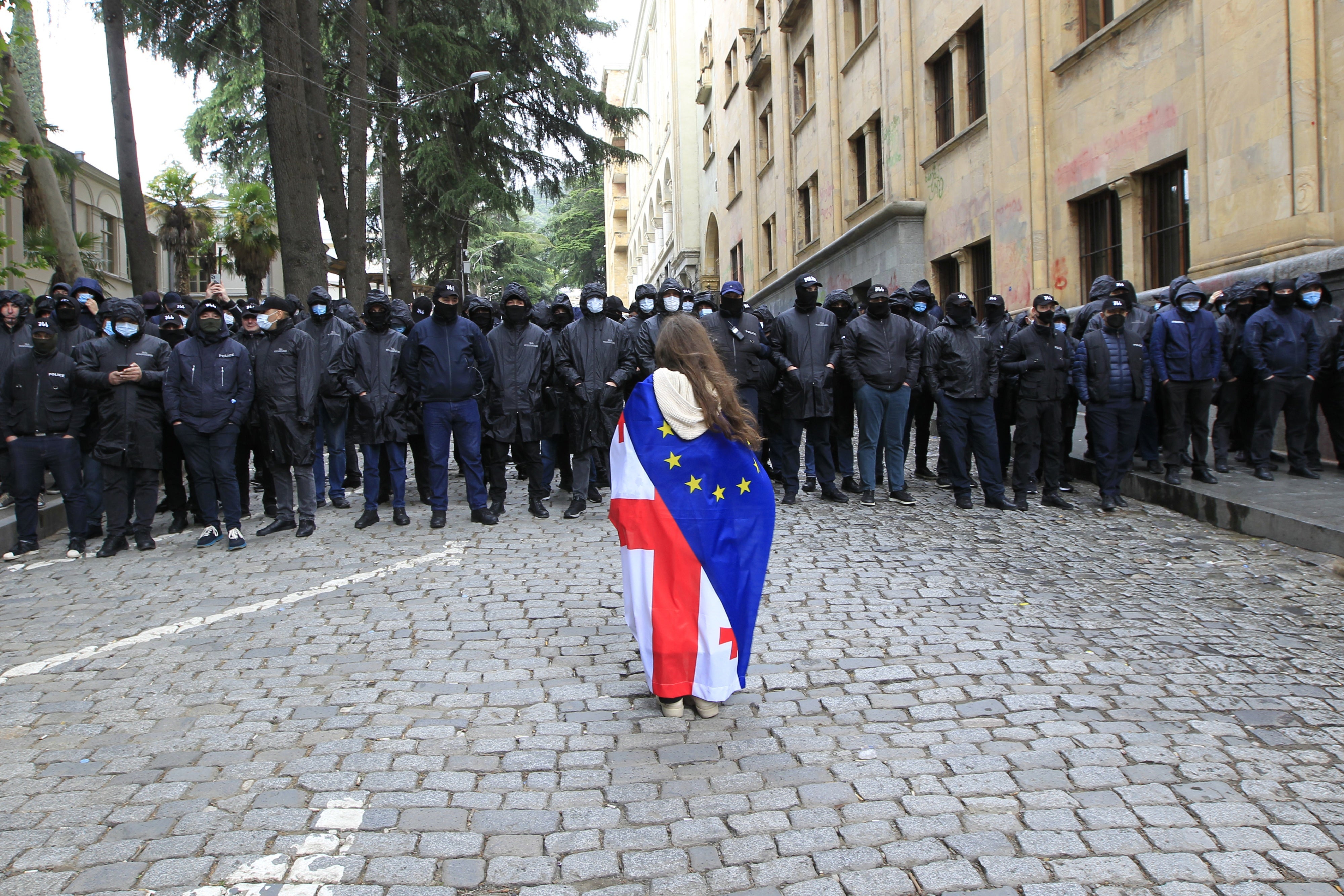 Une manifestante drapée des drapeaux national géorgien et européen se tient devant la police, qui bloque l'accès au bâtiment du parlement, lors d'une manifestation contre la loi sur les "agents de l'étranger" à Tbilissi, en Géorgie, le 14 mai 2024.