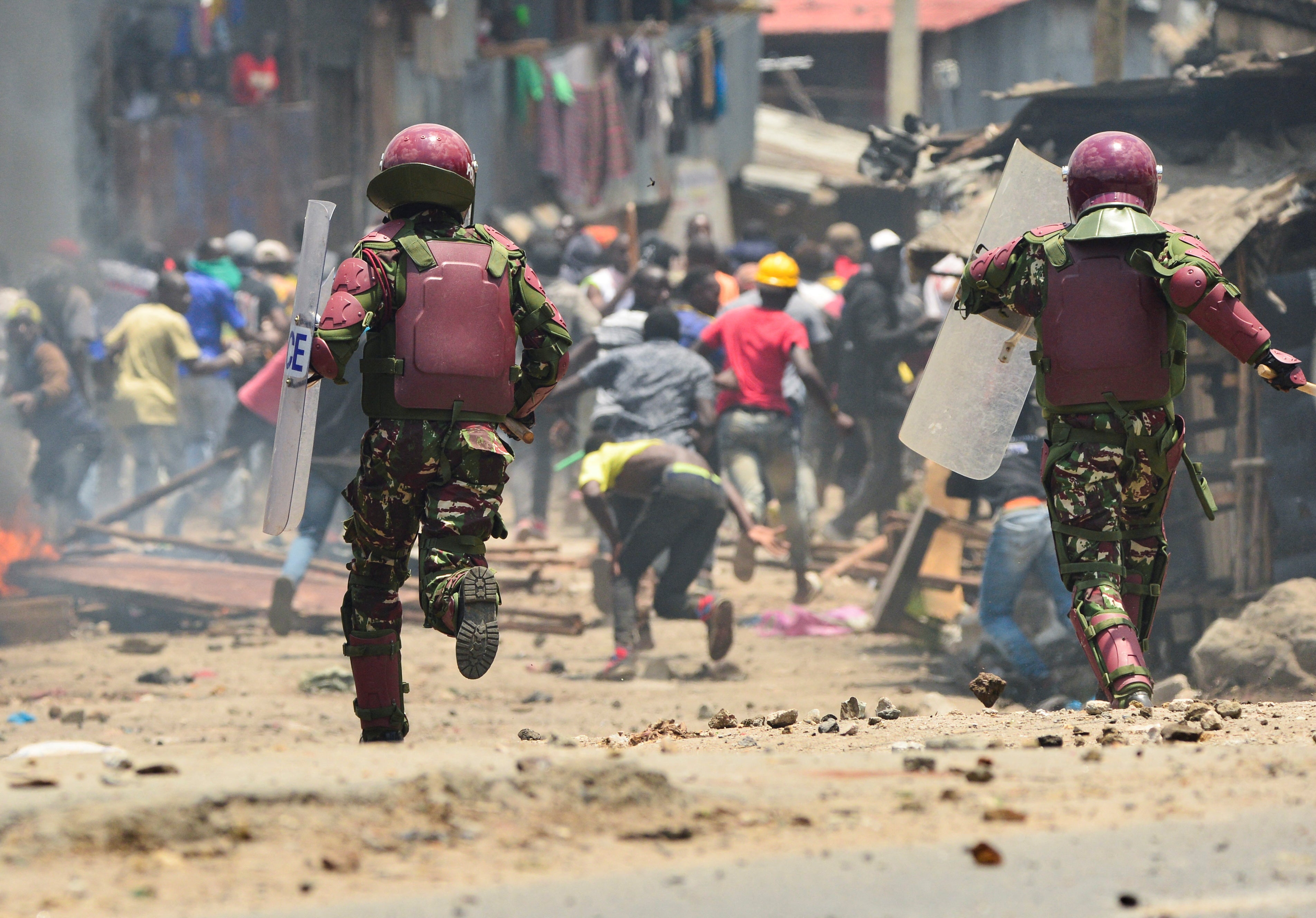 Armed riot police officers run towards protesters 