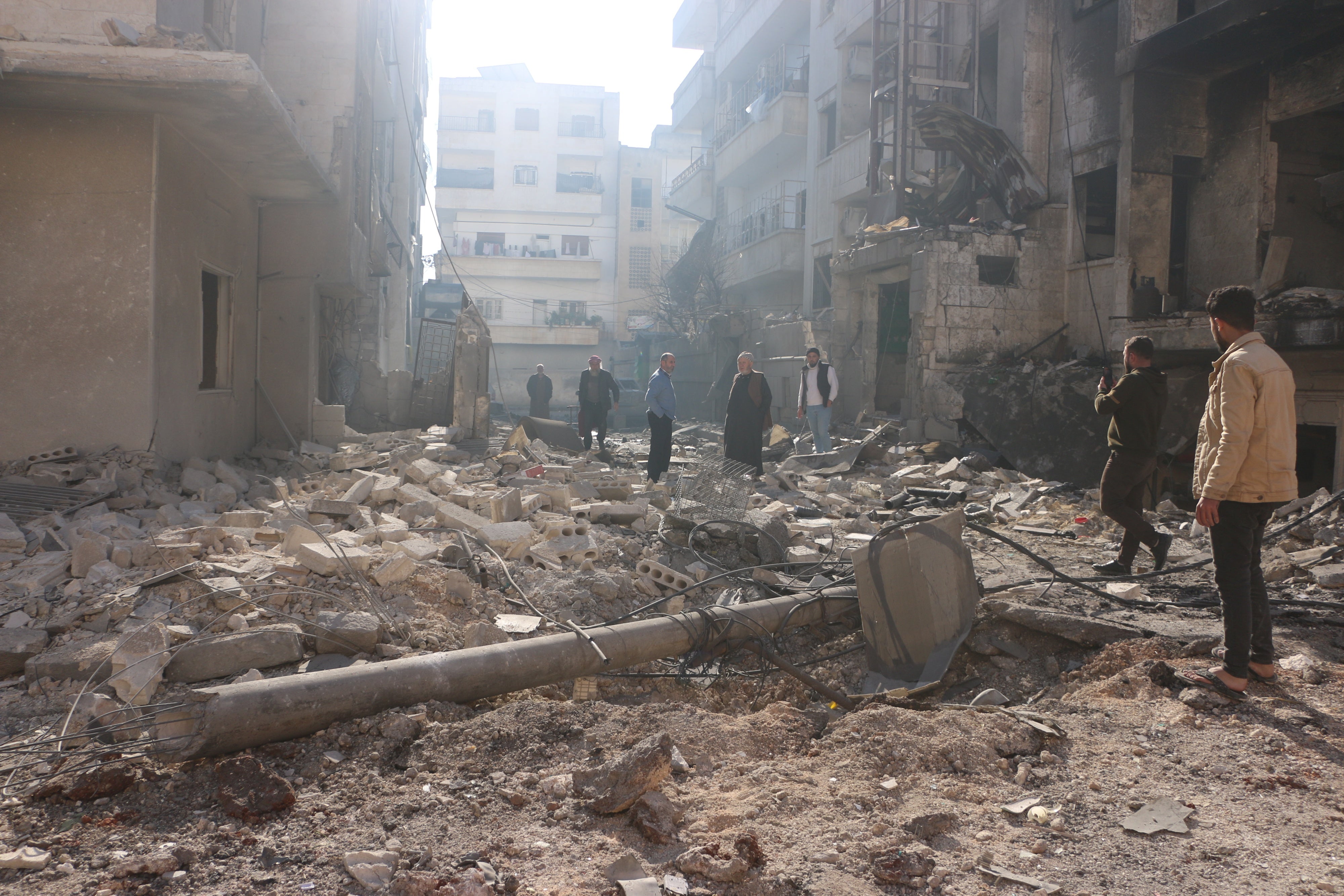 Des habitants d’Idlib, dans le nord-ouest de la Syrie, marchaient parmi les décombres dans une rue d’un quartier résidentiel du centre-ville, suite à une frappe aérienne menée par l’armée syrienne, le 1er décembre 2024.