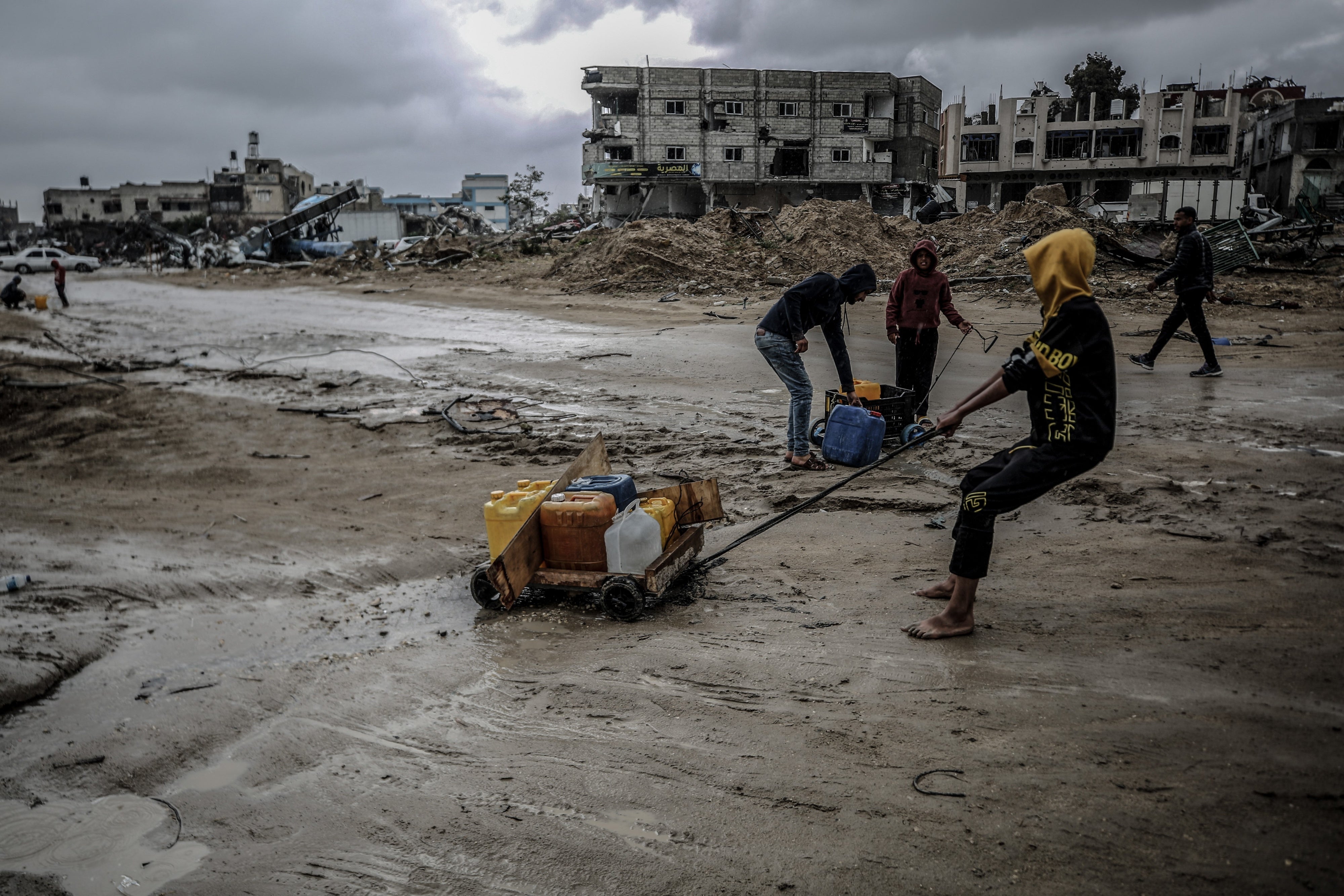 Palestinesi tornano a Khan Younis dopo il ritiro delle forze israeliane, trascinando contenitori d'acqua per soddisfare le loro necessità vitali in condizioni catastrofiche, il 6 maggio 2024. 