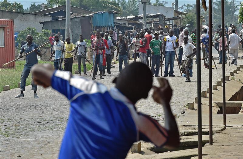 Un manifestant lance une pierre à des membres des Imbonerakure.