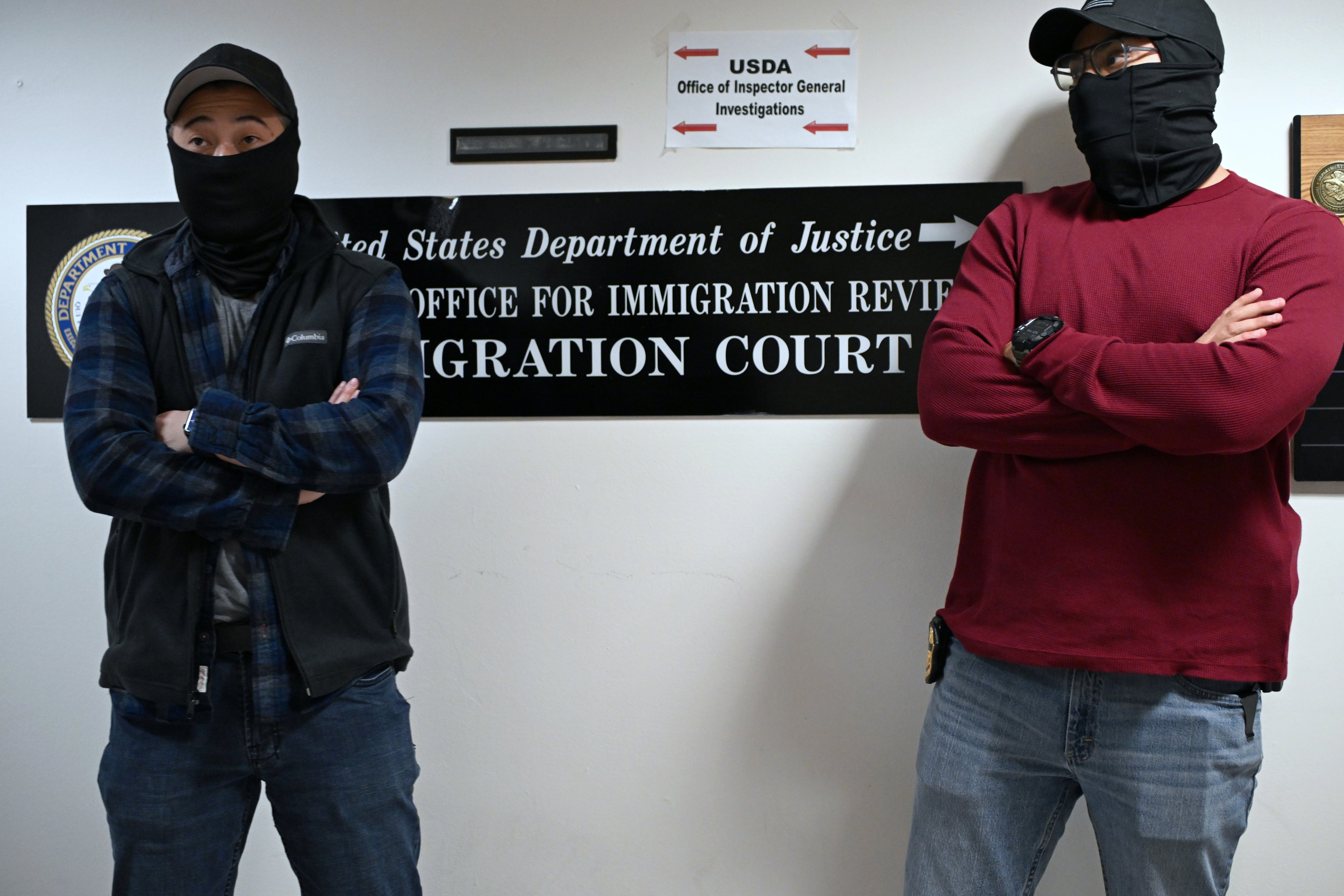 Deux agents de l'Autorité de l’immigration et des douanes (Immigration and Customs Enforcement, ICE), portant des masques, photographiés près de l’entrée du tribunal de l'immigration situé au 26 Federal Plaza à Manhattan, New York, le 31 octobre 2025. 