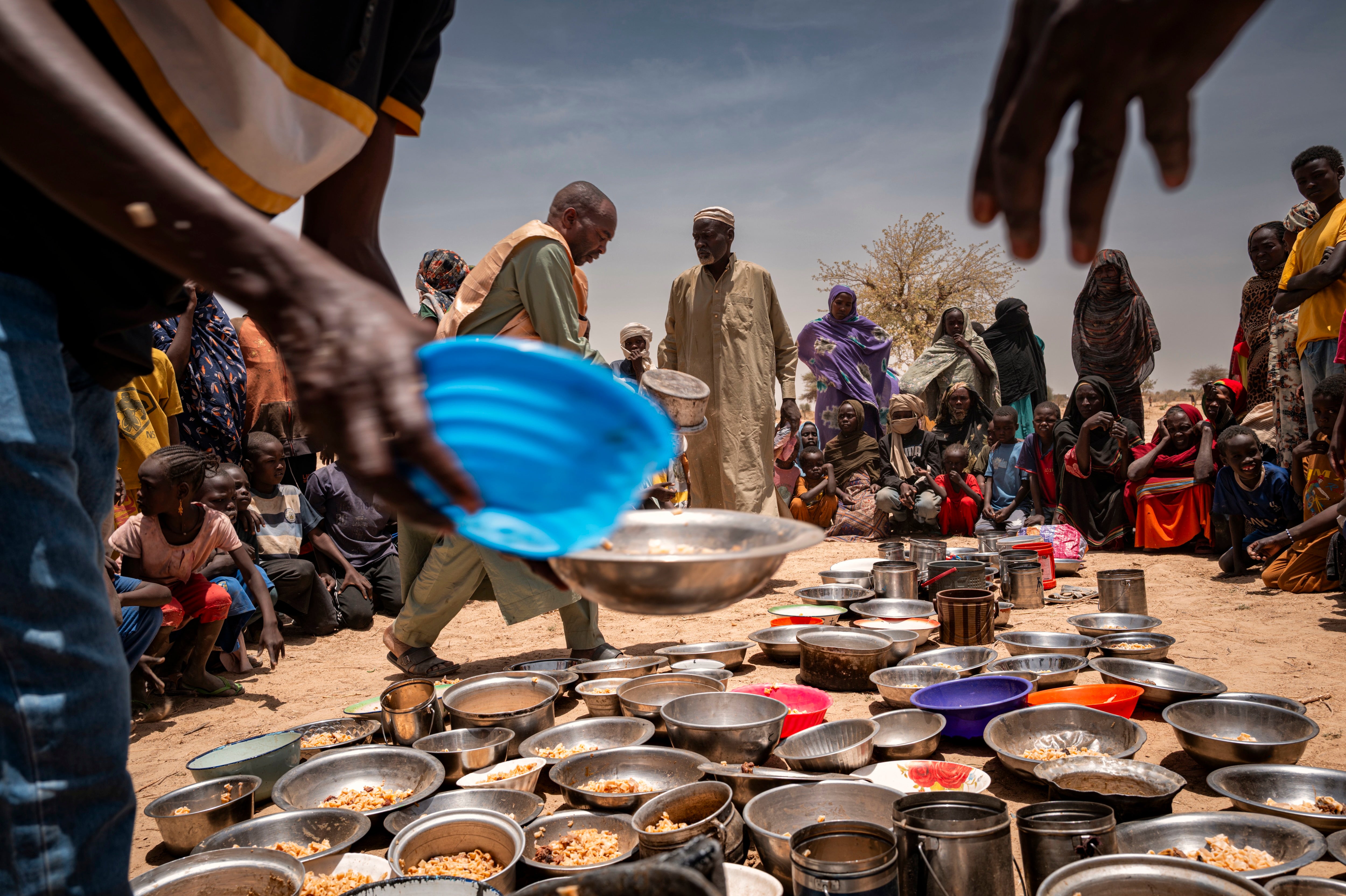 Sudanesische Geflüchtete aus dem Zamzam-Lager außerhalb von El Fasher in Darfur erhalten während ihrer Umsiedlung in das Transitlager Iridimi in Tine im Osten des Tschad Lebensmittel in einer Gemeinschaftsküche der Notfallhilfe, 4. Mai 2025.