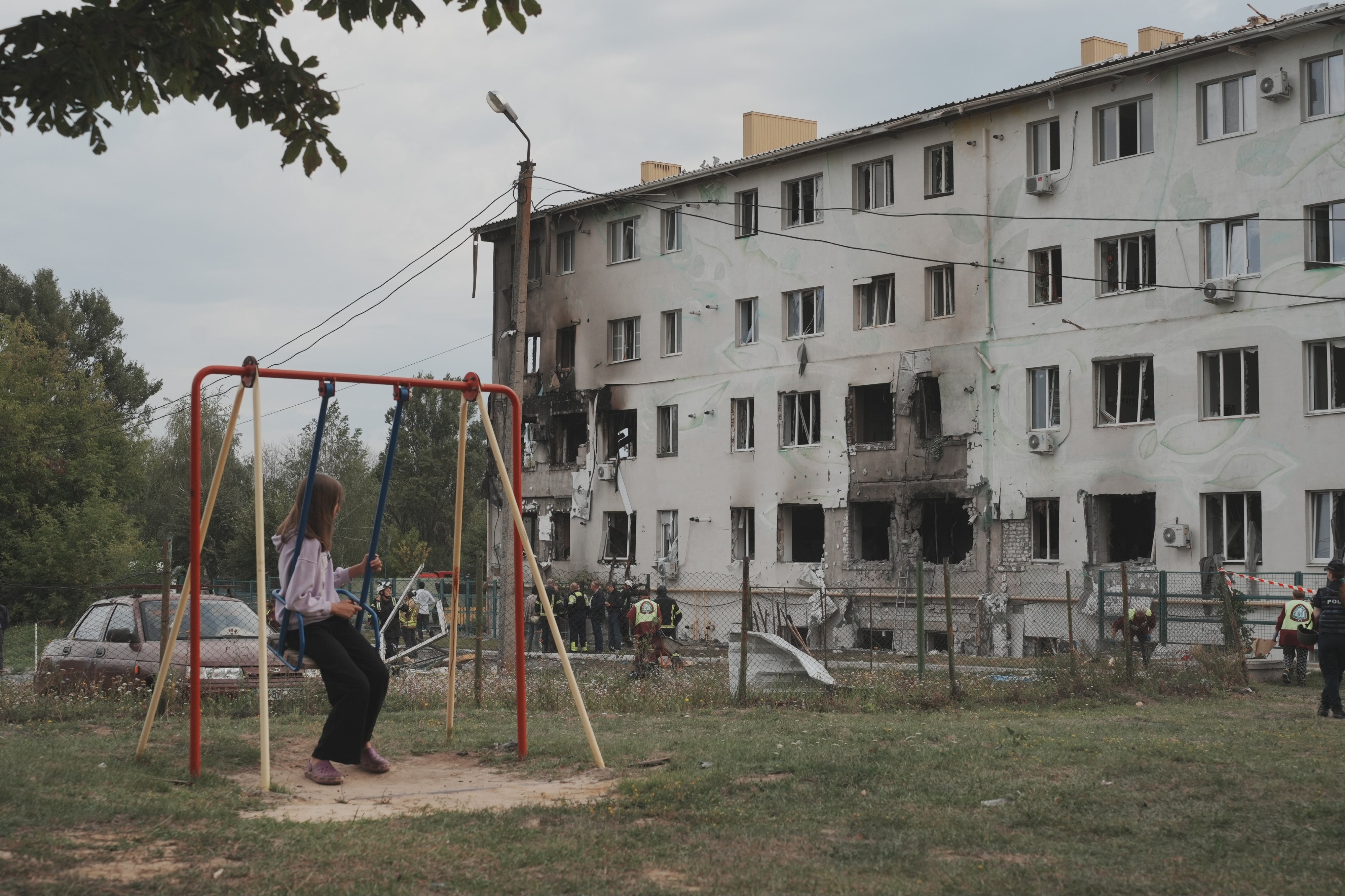 Una niña en un columpio mira un edificio de apartamentos en el distrito Industrialnyi de Járkov, Ucrania, dañado por un ataque con drones rusos que mató a 7 personas (entre ellas niños) e hirió a 23, el 18 de agosto de 2025.