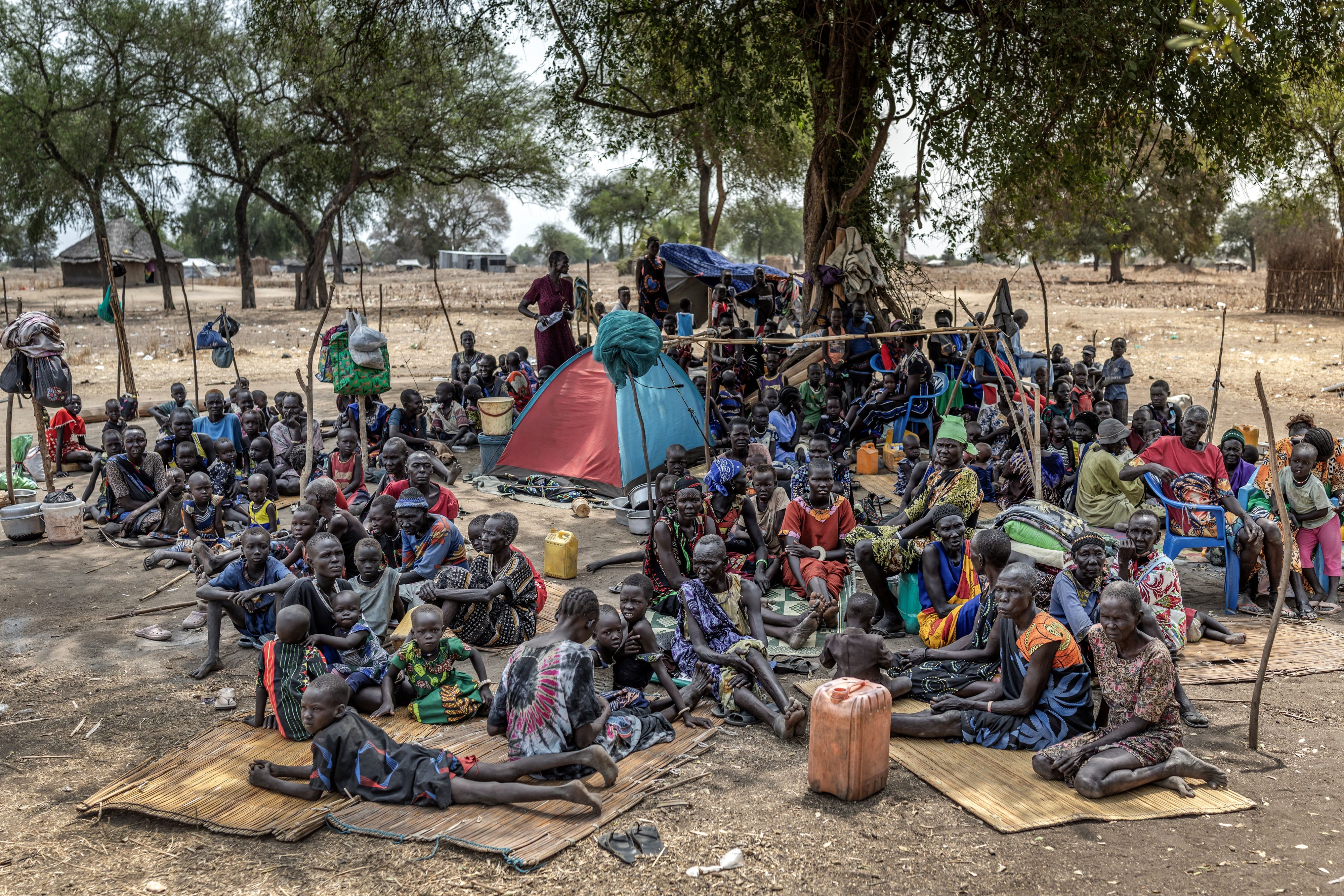 Families gather under a tree at an informal site where displaced people, many from neighboring Jongeli state, have assembled without assistance or shelter at Yolakot informal camp near Mingkaman, Lakes state on February 14, 2026. 
