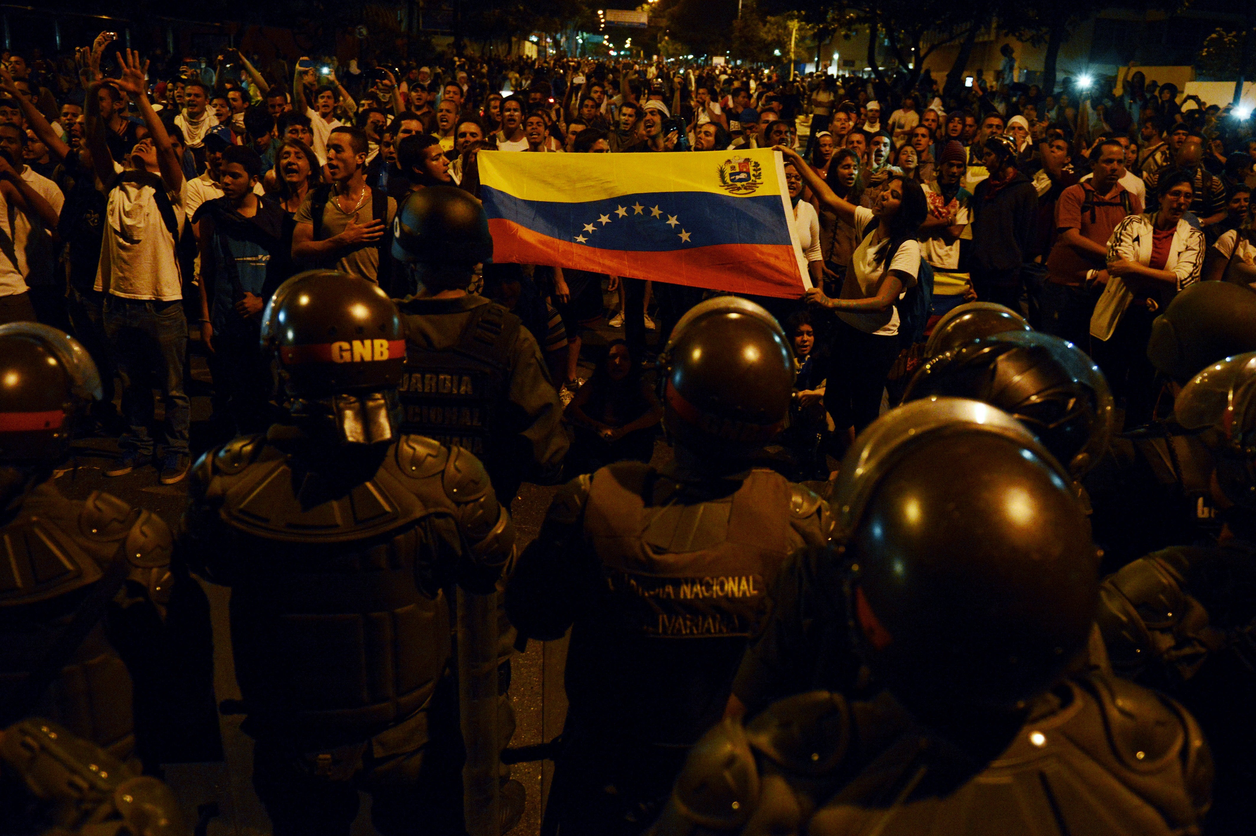 Anti-government students show a national flag to a National Guard barricade during a protest in Caracas, Venezuela, on February 16, 2014. 