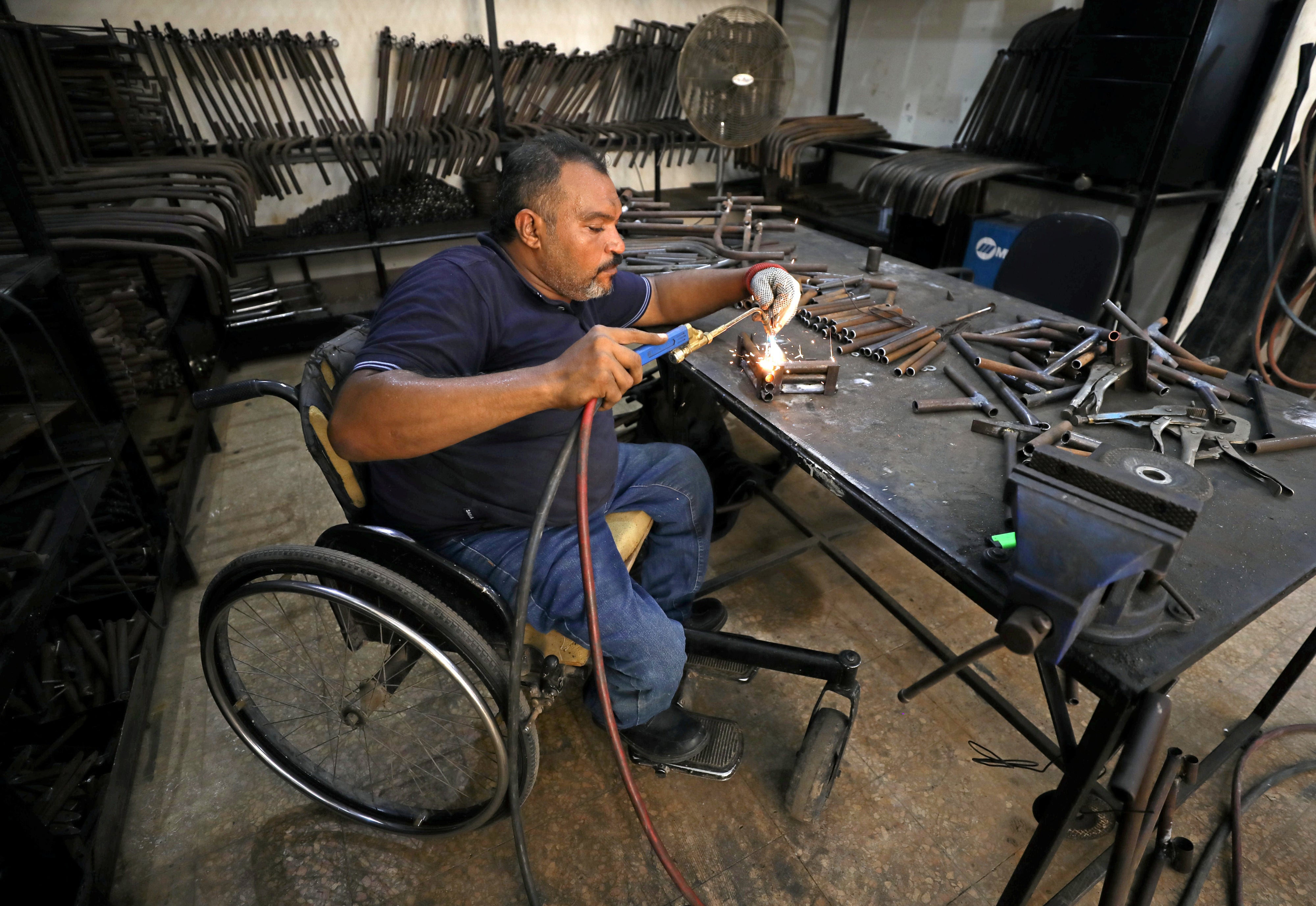  Un homme atteint d'un handicap physique fabriquait des pièces pour des fauteuils roulants et d’autres produits de mobilité pour des personnes handicapées, vivant notamment dans des quartiers défavorisés, dans un atelier au Caire, en Égypte, le 8 août 2017. 