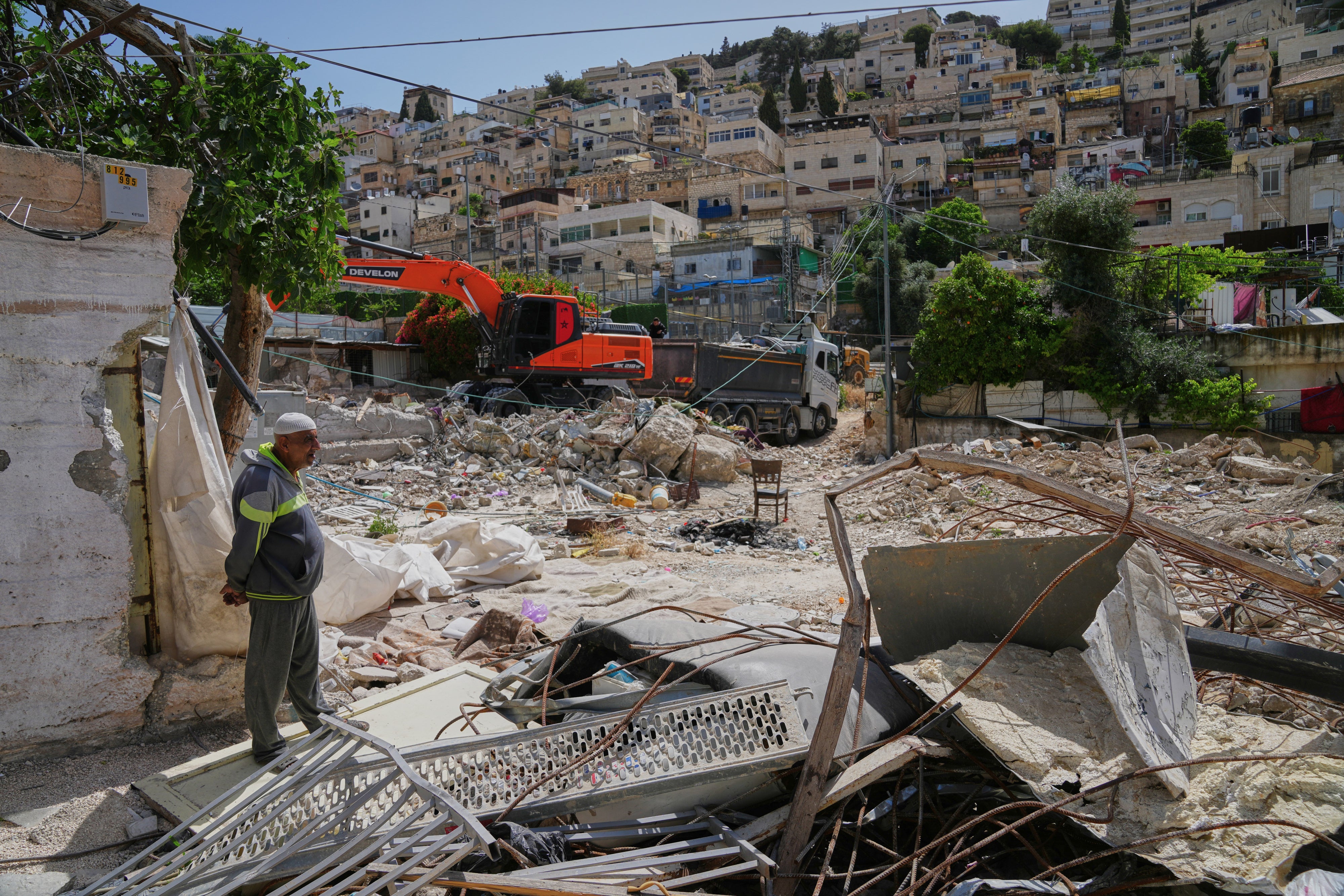 A Palestinian man looks on as an excavator clears the rubble of homes demolished by Israeli authorities in the Silwan neighborhood of east Jerusalem, May 19, 2026.