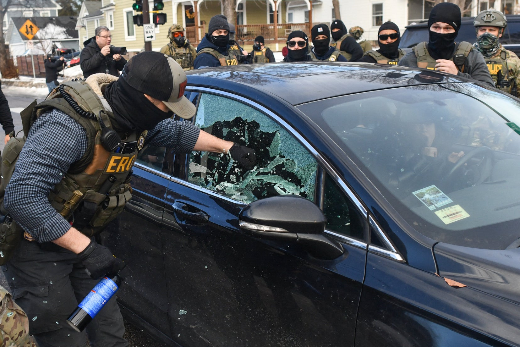 An ICE agent breaks a car window