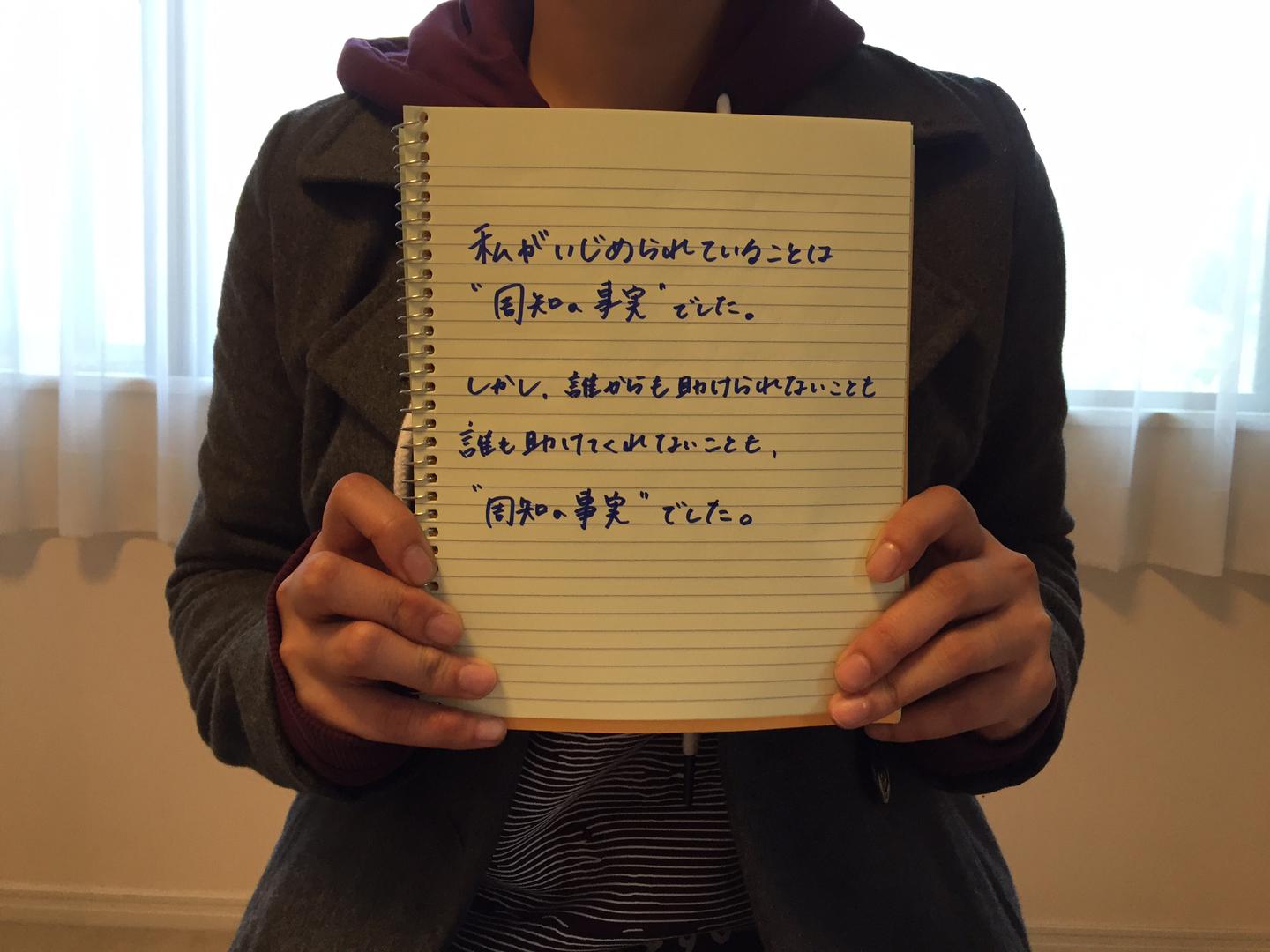 A 20 year old Japanese woman who was bullied by her classmates in junior high school holds a notebook displaying the message...