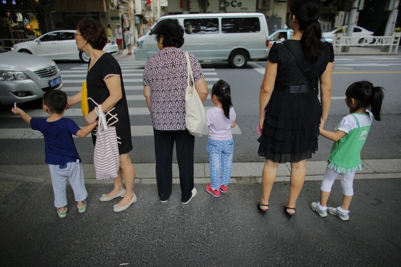 上海闹区，妇女们牵着孩子准备过马路，2014年9月12日。