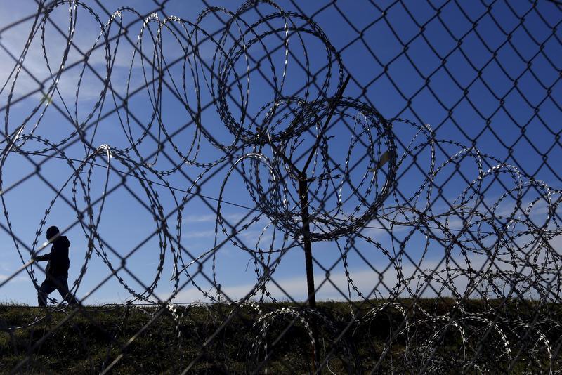 Migrants walk along Hungary's border fence on the Serbian side of the border near Morahalom, Hungary, February 22, 2016
