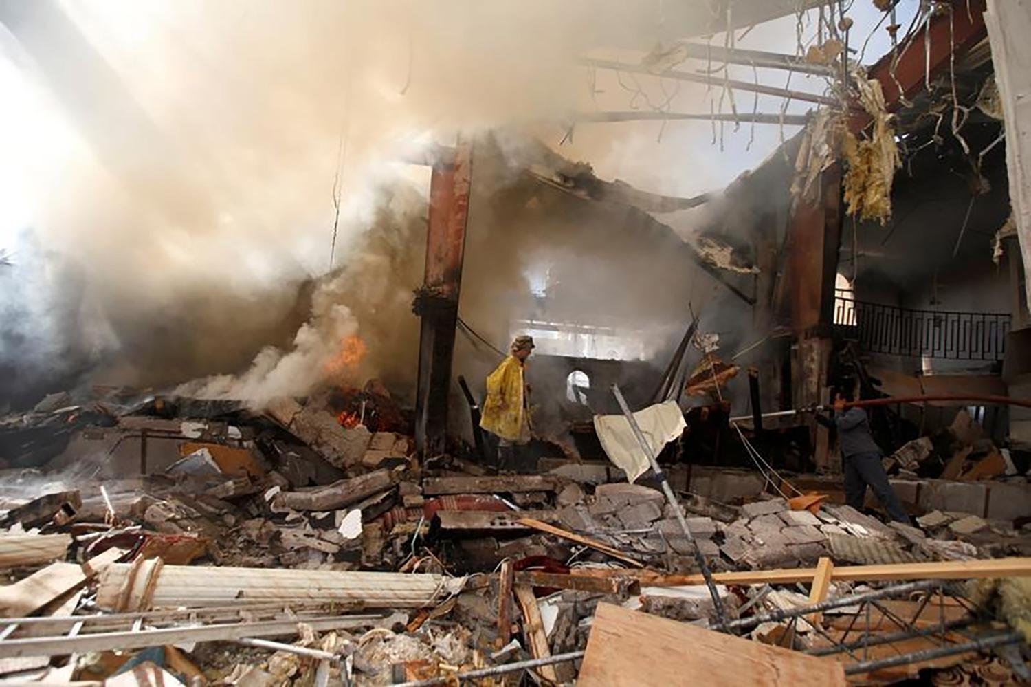 Firefighters try to extinguish a fire at the community hall in Sanaa where Saudi-led coalition warplanes attacked a funeral on October 8, 2016. 