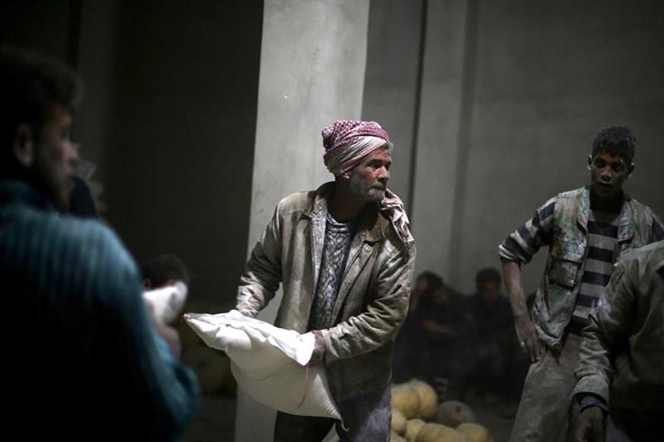 Men store bags of flour unloaded from a Red Crescent aid convoy in the rebel-held, besieged town of Jesreen in Eastern Ghouta, Syria on March 7, 2016. 