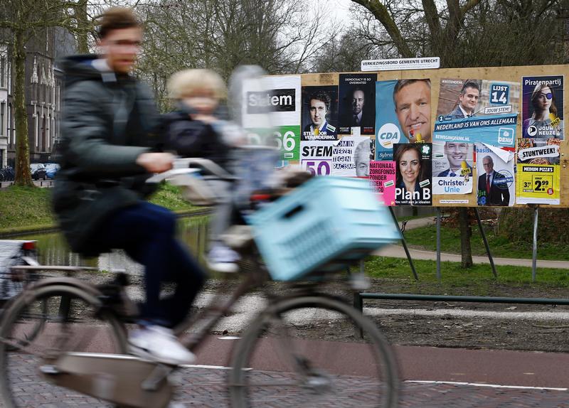 A man and child cycle past an election poster billboard the day before a general election, in Utrecht, Netherlands, March 14, 2017.