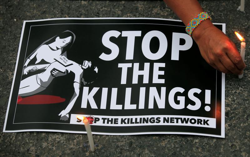 A protester lights candles next to a placard, seeking justice for killings in President Rodrigo Duterte's war on drugs, during a protest in front of the Philippine National Police (PNP) headquarters in Quezon city, Metro Manila, Philippines August 23, 201