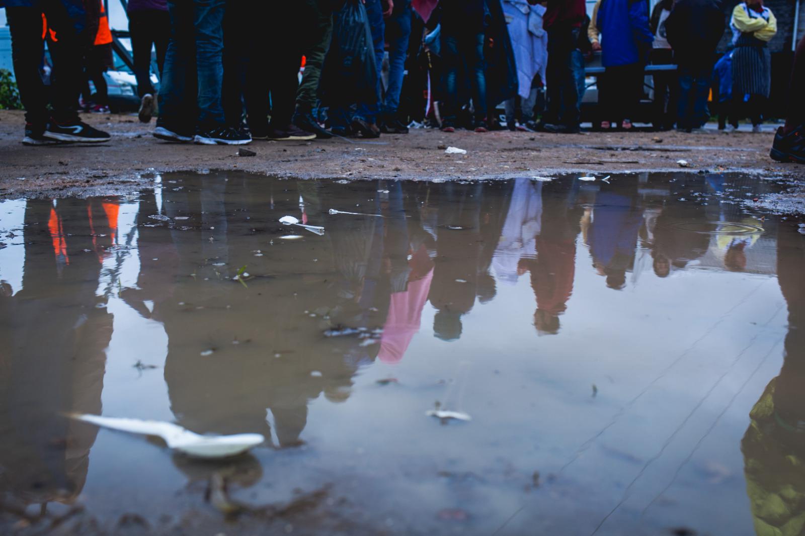 Les migrants à Calais se rassemblent sous la pluie pour une distribution de vêtements dans une zone industrielle à la périphérie de Calais, en France.
