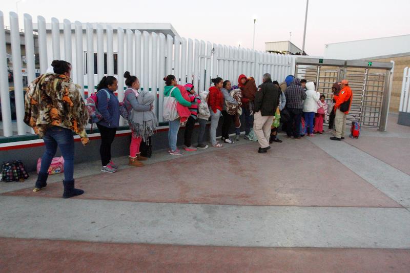 Immigrants from Central America and Mexican citizens, who are fleeing from violence and poverty, queue to cross into the U.S. to apply for asylum.