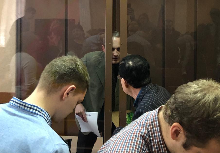 Dennis Christensen (behind the windows) talks with his interpreter at the Zheleznodorzhy District Court in Oryol, January 28, 2019