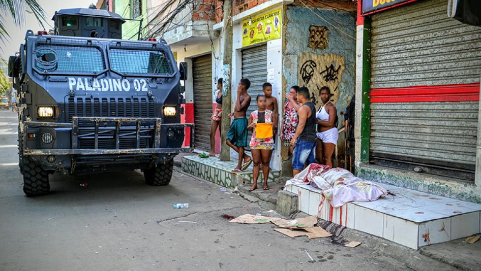 A military police armored vehicle passes by a person killed by police on April 7, 2016 in the Jacarezinho favela. Military police killed tow other people during the same raid. 