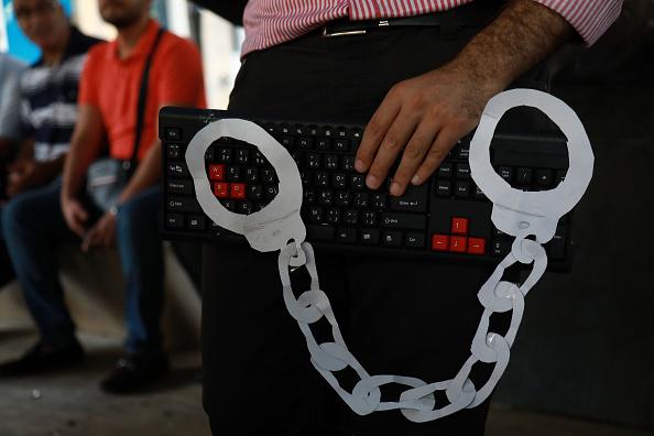 ناشط يحمل كيبورد حاسوب وأصفاد مصنوعة من ورق في وسط بيروت يوم 24 يوليو/تموز 2018 خلال اعتصام ضد الموجة الأخيرة من الاستدعاءات الأمنية بحق الأشخاص الذي يدلون بتعليقات سياسية في لبنان.