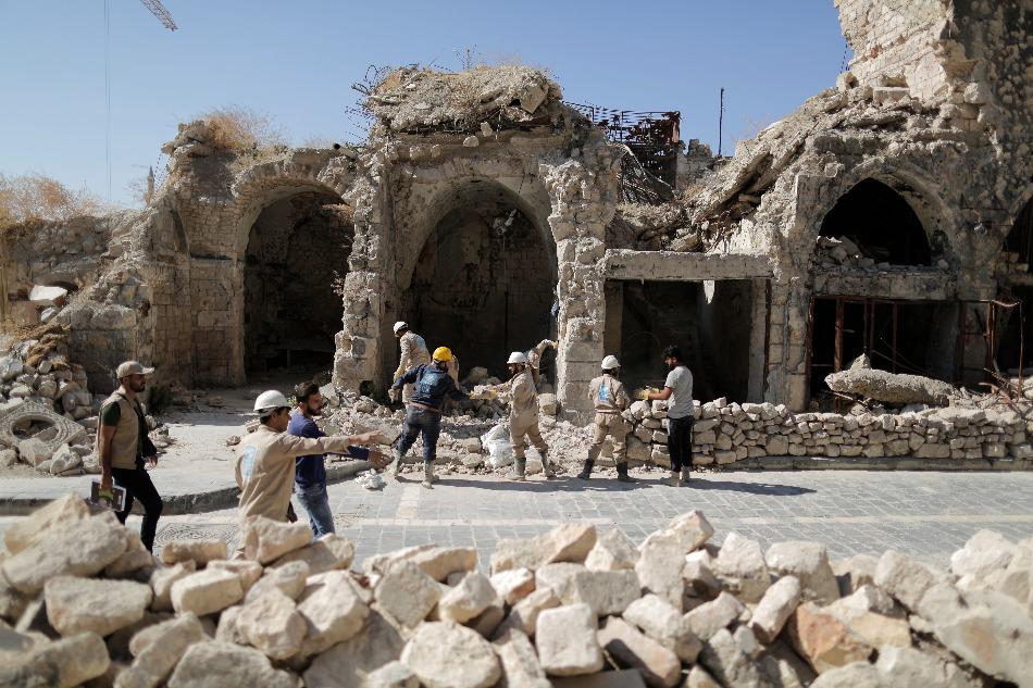 عمال يُزيلون الأنقاض من متجر مُتضرر في المدينة القديمة في حلب، سوريا، 27 يوليو/تموز 2019.