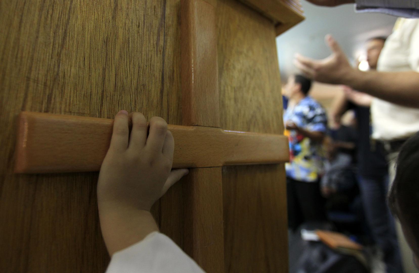 Un jeune garçon protestant berbère pose sa main sur une croix en bois, lors d’une une messe célébrée dans une église protestante de la ville de Tizi Ouzou, située à 100 kilomètres à l'est d’Alger, en Algérie, le 2 octobre 2010. 