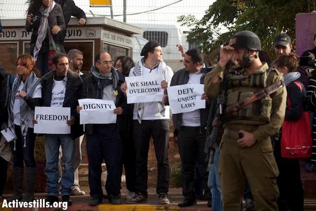 פעילים פלסטינים ממתינים לעלות לאוטובוס ישראלי המקשר בין התנחלות ישראלית בגדה המערבית למזרח ירושלים הכבושה כדי למחות על הגבלות מפלות על תנועה, 15 בנובמבר 2011.