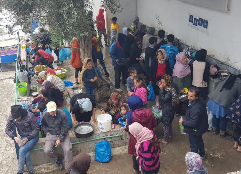 People in the Moria refugee camp on the Greek island of Lesbos wait to use one of the few overcrowded water stations in the camp.