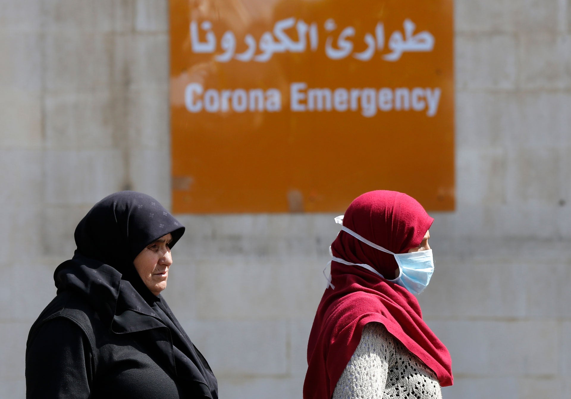 أشخاص يعبرون أمام مدخل قسم الطوارئ في مستشفى رفيق الحريري الجامعي الحكومي حيث تُعالَج معظم الإصابات بفيروس كورونا في لبنان، بيروت، لبنان في 11 مارس/آذار 2020. 