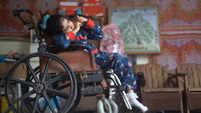 Deema Salha, an 11-year-old girl with cerebral palsy and an intellectual disability, in the yard of her home in the Gaza Strip. Deema uses a nebulizer when she has trouble breathing, which she cannot operate without electricity, putting her health at risk.