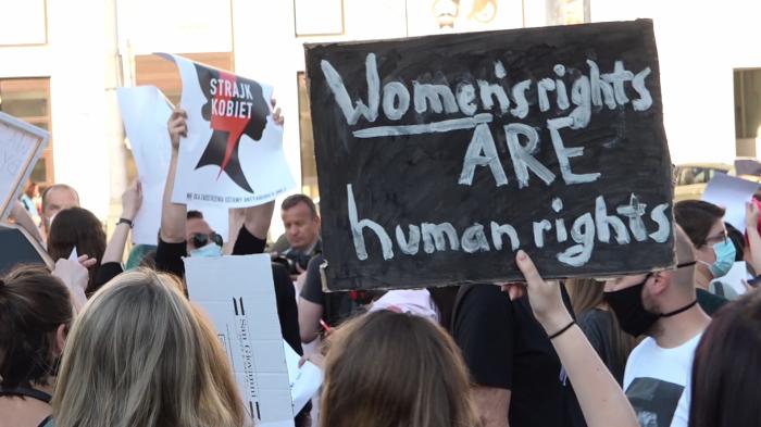 Demonstrantinnen erinnern mit einem Protestschild daran, dass Frauenrechte Menschenrechte sind.