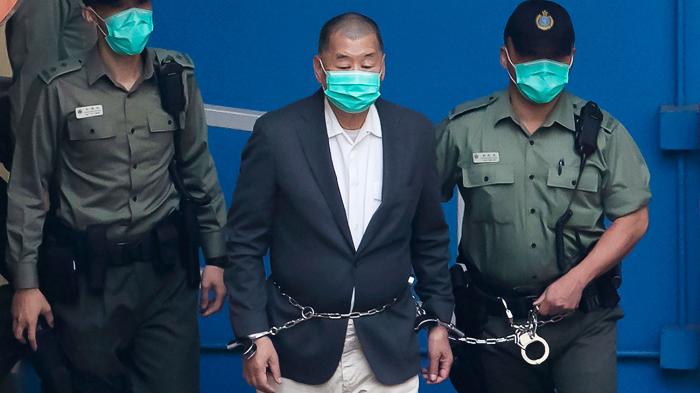 In this December. 12, 2020, file photo, Jimmy Lai,  center, who founded the pro-democracy newspaper Apple Daily, is escorted by Correctional Services officers to get on a prison van before appearing in a court.
