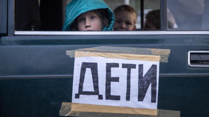 Children from Mariupol, Ukraine, look out the window of their family’s car, marked with the word “children,” after arriving at an evacuation point for people fleeing areas under Russian control.