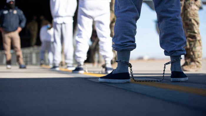 People in ankle chains board a plane