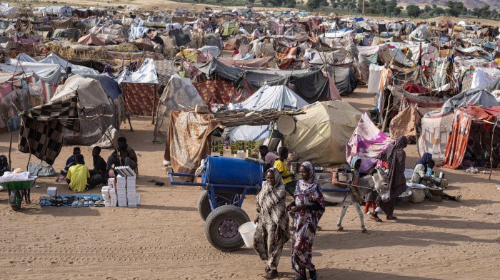 Displaced Sudanese people who fled El-Fasher after the city fell to the Rapid Support Forces (RSF), walk in the Um Yanqur camp, located on the southwestern edge of Tawila, in western Darfur, on November 3, 2025.