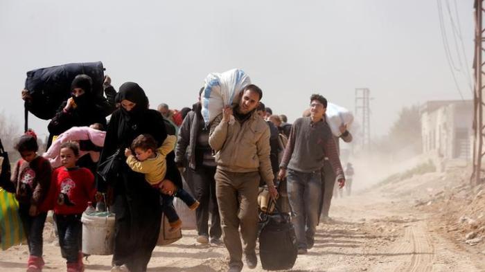 People walk with their belongings as they flee the rebel-held town of Hammouriyeh, in the village of Beit Sawa, eastern Ghouta, Syria March 15, 2018. REUTERS/Omar Sanadiki