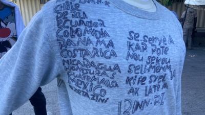 Un Haïtien renvoyé au pays par les États-Unis en décembre 2021 a noté sur un pullover tous les pays qu’il a dû traverser pour arriver jusqu’aux États-Unis, en commençant par la République dominicaine. L’inscription à droite dit en créole : « Notre secours est dans le nom de l'Éternel, Qui a fait les cieux et la terre. »