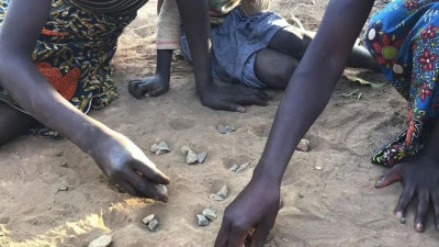 Figures' hands lay in the sand.